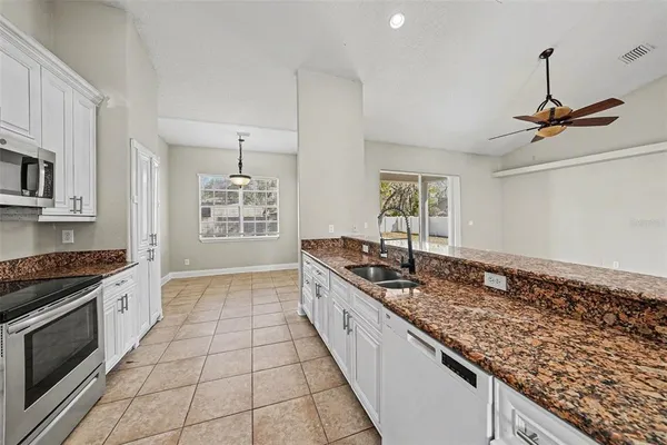 a kitchen with granite countertop a stove a sink and a refrigerator
