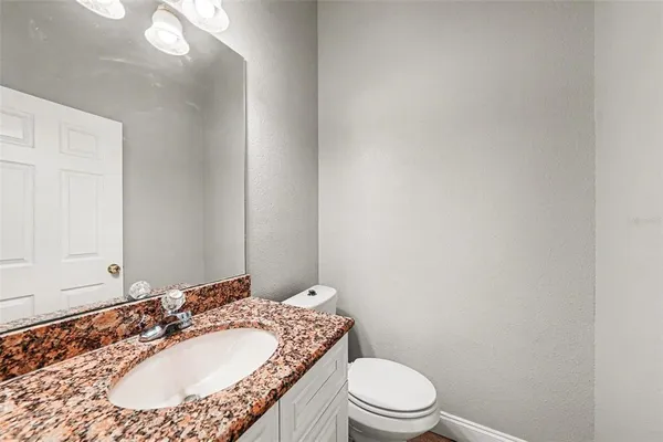 a bathroom with a granite countertop sink a toilet and a mirror