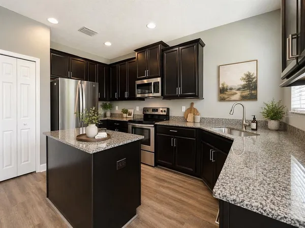a kitchen with stainless steel appliances granite countertop a refrigerator a sink dishwasher a stove and a oven with wooden floor
