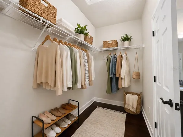 a walk in closet with wooden floor