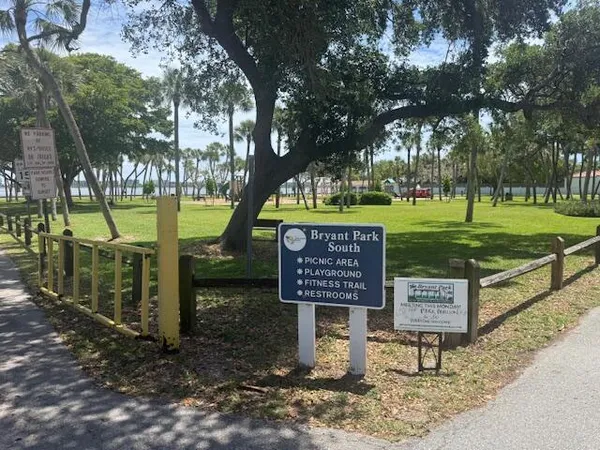 a sign board with a bench and trees
