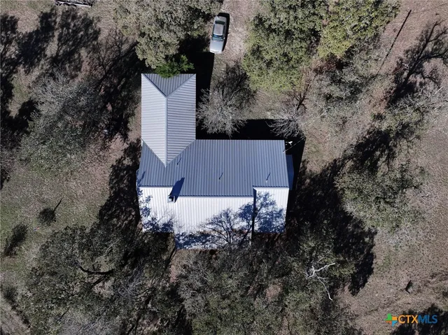 an aerial view of house with yard and trees all around
