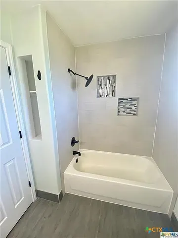 a white bath tub sitting next to a white wall