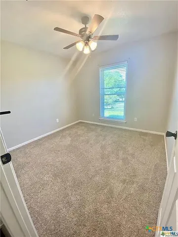 an empty room with windows and fan
