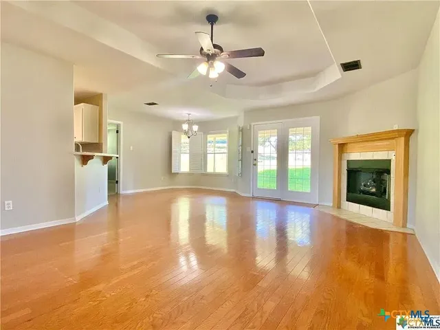 a view of an empty room with window and wooden floor