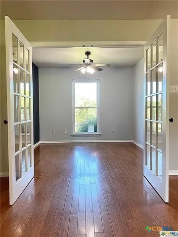 a view of an empty room with wooden floor and a window
