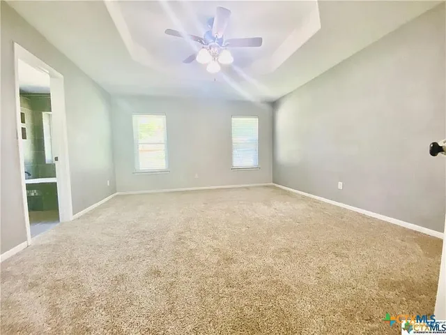 an empty room with windows and chandelier fan