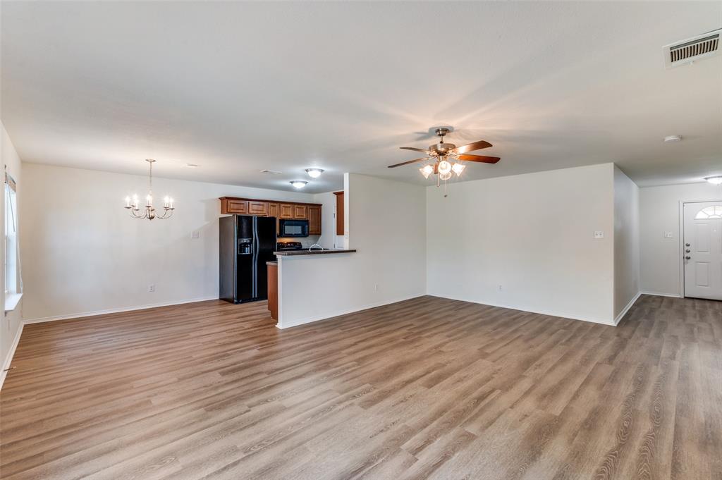 1012 Barbara Street Denton, TX 76209 - Photo 11 of 23 a view of an empty room with wooden floor and a kitchen