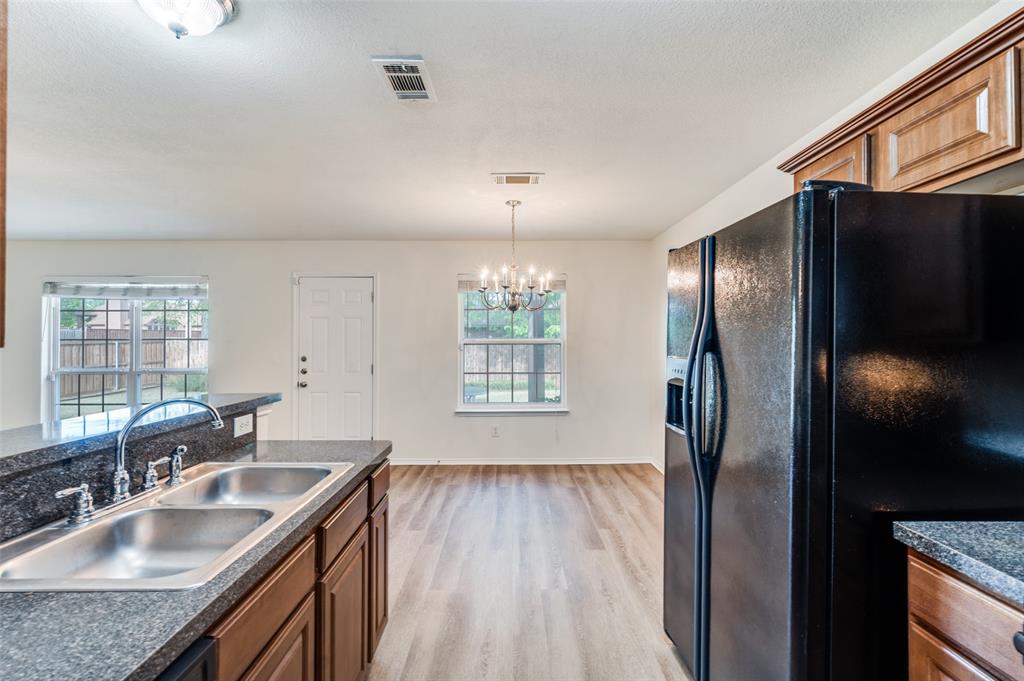 1012 Barbara Street Denton, TX 76209 - Photo 4 of 23 a kitchen with stainless steel appliances granite countertop a refrigerator a sink dishwasher a stove and white countertops with wooden floor