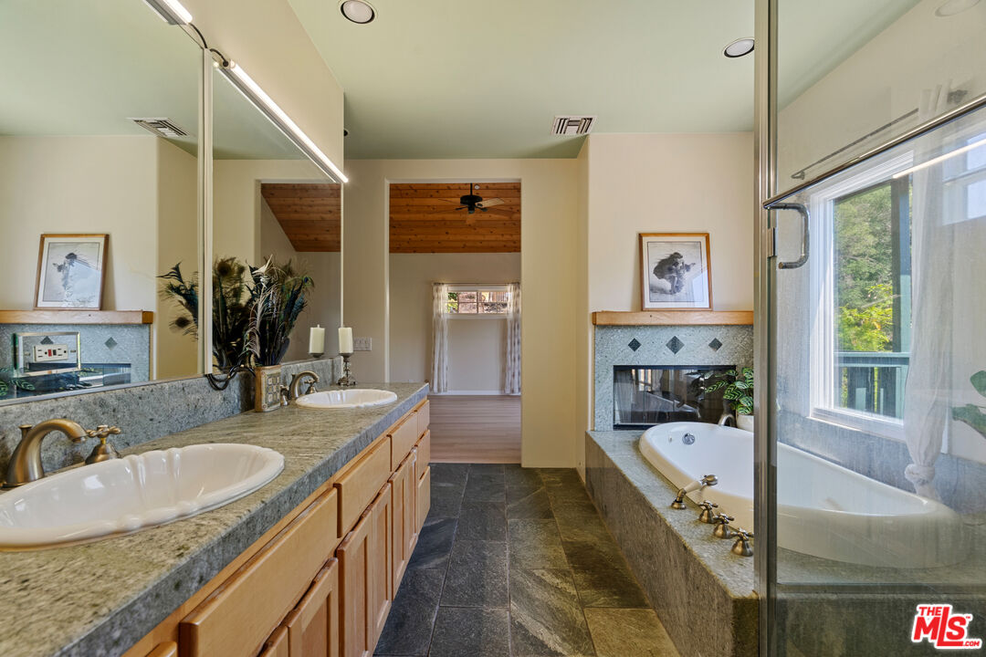 20912 Fontaine Road Topanga, CA 90290 - Photo 24 of 52 a bathroom with a granite countertop sink a mirror and a bathtub