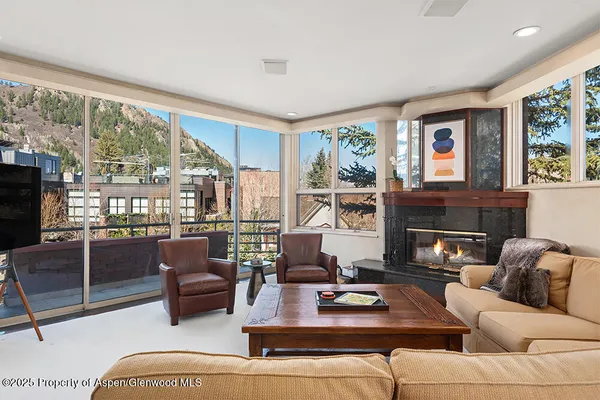 a living room with furniture large windows and a fireplace