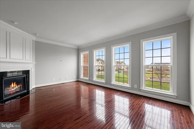 an empty room with wooden floor fireplace and windows