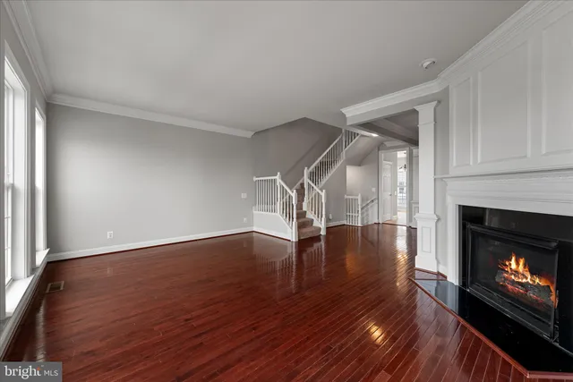 a view of an empty room with wooden floor fireplace and a window