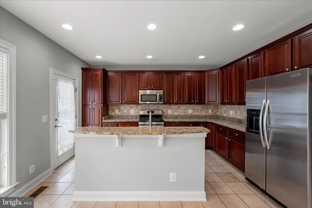 a kitchen with kitchen island granite countertop wooden cabinets a refrigerator and a sink