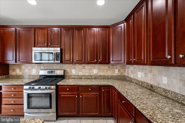 a kitchen with granite countertop wooden cabinets a sink and a stove top oven