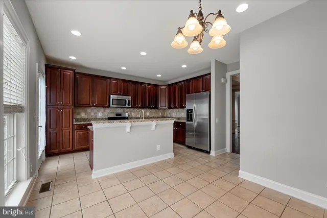 a kitchen with kitchen island granite countertop appliances cabinets and a chandelier