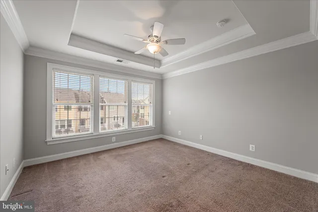an empty room with chandelier fan and windows