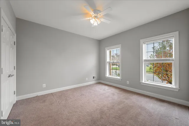 an empty room with windows and ceiling fan