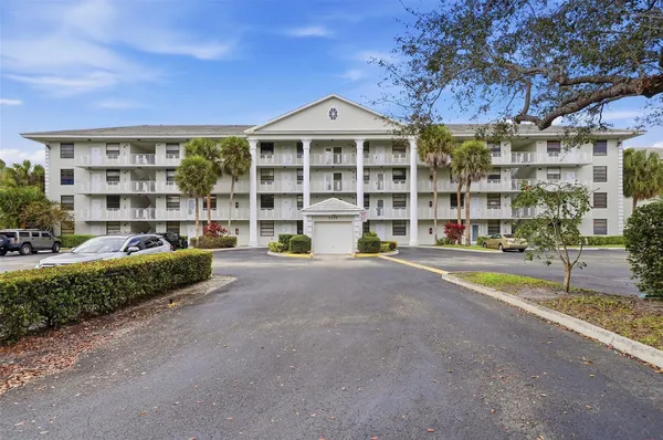 a front view of a building with a garden and parking space