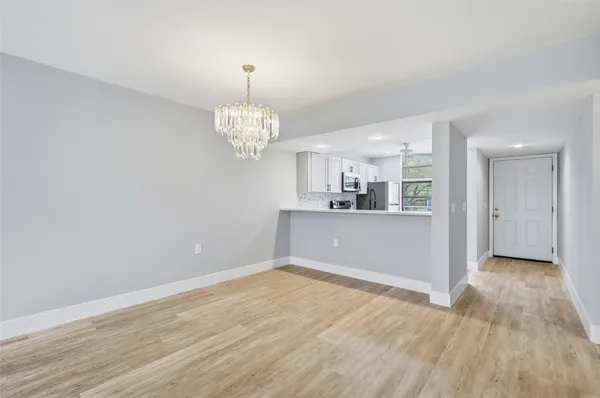 a view of a room with wooden floor and kitchen view