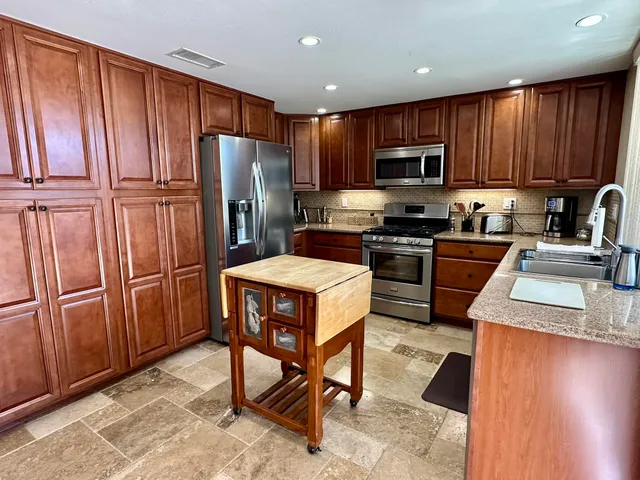 a kitchen with stainless steel appliances granite countertop a refrigerator stove microwave and sink