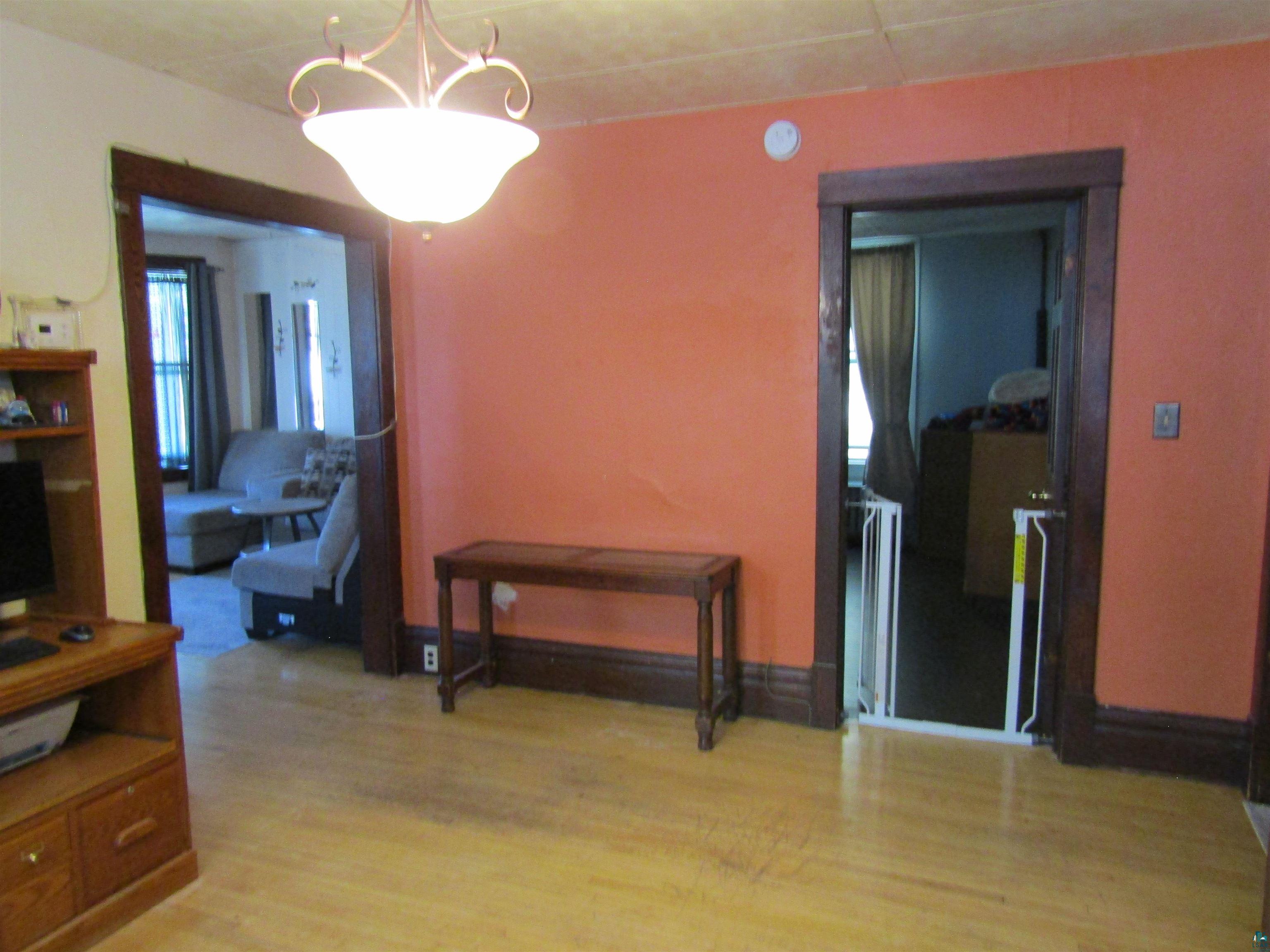1115 Harrison Street Superior, WI 54880 - Photo 6 of 49 Bright interior space featuring light wood-finish flooring, a decorative ceiling light fixture, and bold wall color