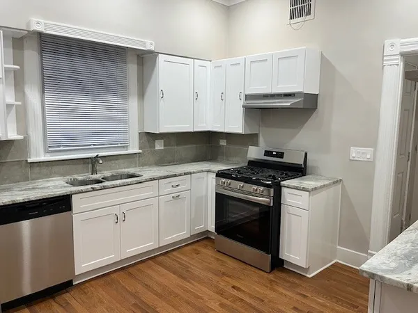 a kitchen with stainless steel appliances granite countertop a stove and white cabinets