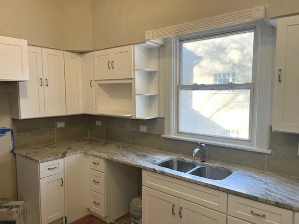 a kitchen with granite countertop a sink window and cabinets