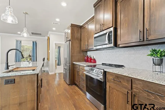 a kitchen with stainless steel appliances granite countertop a sink a stove and a refrigerator