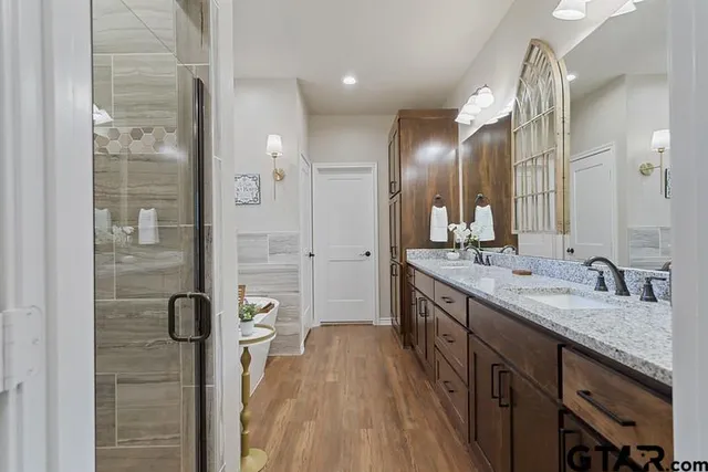 a spacious bathroom with a granite countertop sink a mirror and shower
