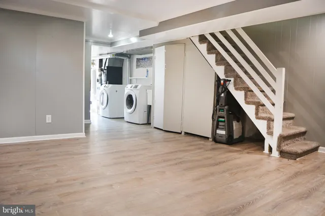 a view of an empty room with wooden floor and stairs