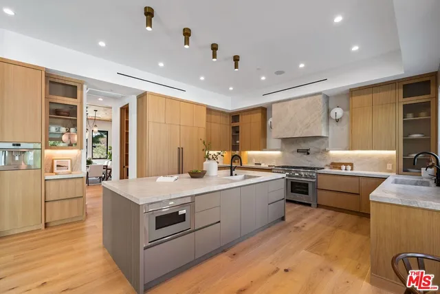 a large kitchen with stainless steel appliances granite countertop a stove oven and a refrigerator with wooden floor