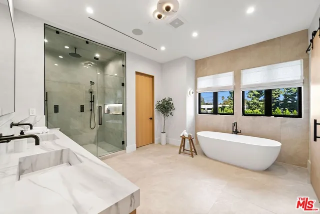 a spacious bathroom with a tub sink a shower and mirror