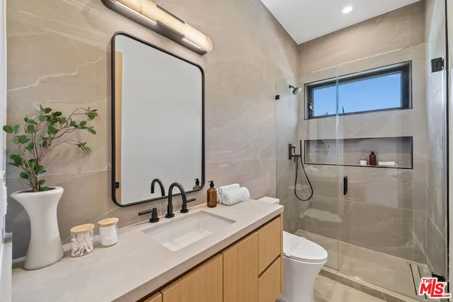 a bathroom with a granite countertop sink mirror vanity and toilet