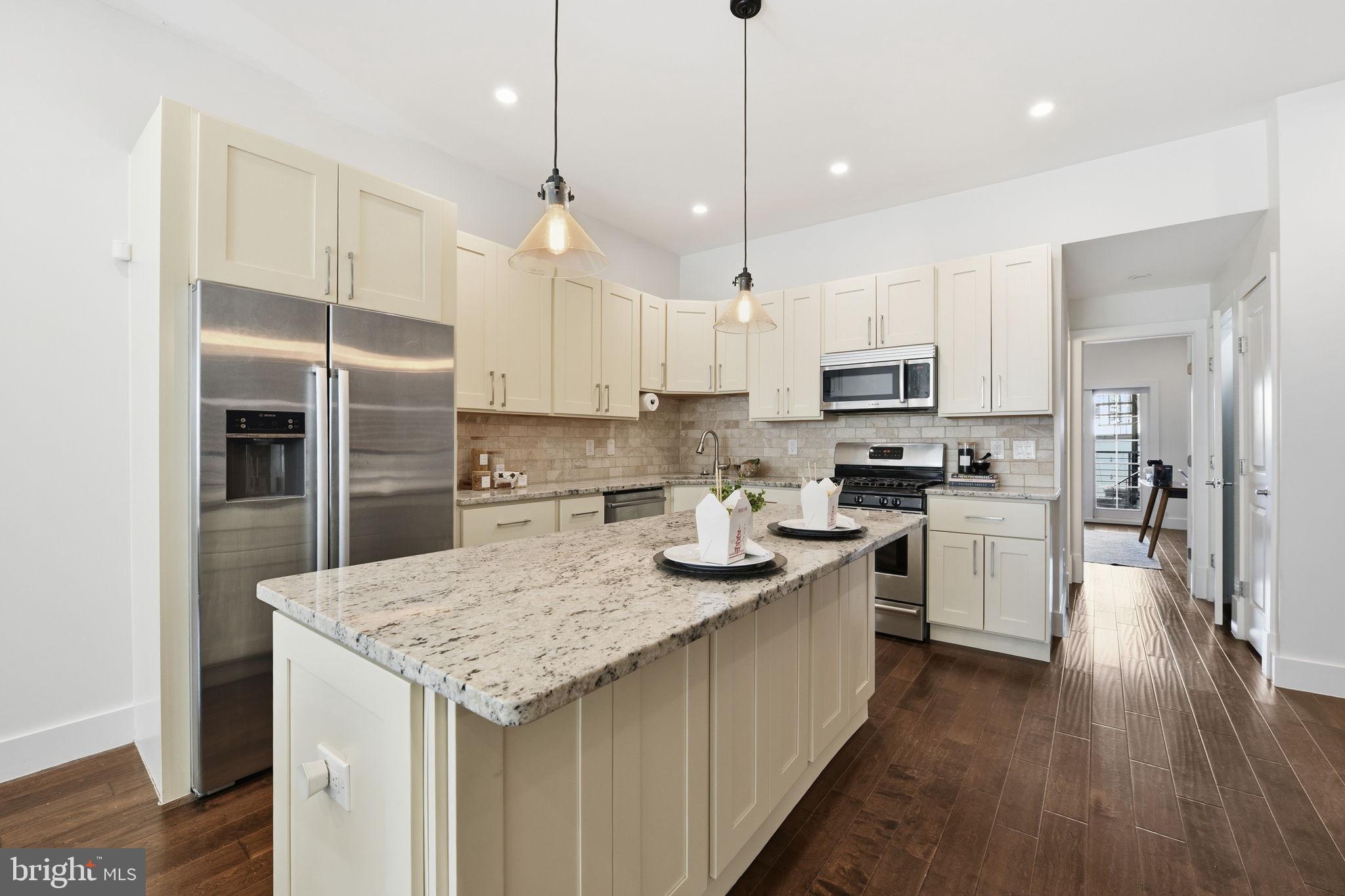 26 Q Street Northeast, Unit 1 Washington, DC 20002 - Photo 14 of 36 a kitchen with kitchen island granite countertop stainless steel appliances and wooden cabinets