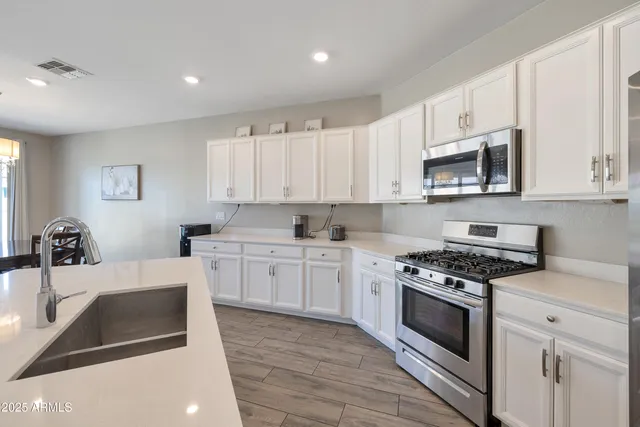 a kitchen with granite countertop a sink a stove and cabinets