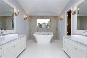 a spacious bathroom with a double vanity sink mirror and bathtub