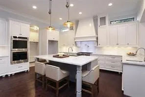 a kitchen with a sink a stove a refrigerator and white cabinets with wooden floor