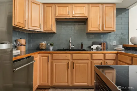 a kitchen with stainless steel appliances granite countertop a refrigerator and wooden cabinets