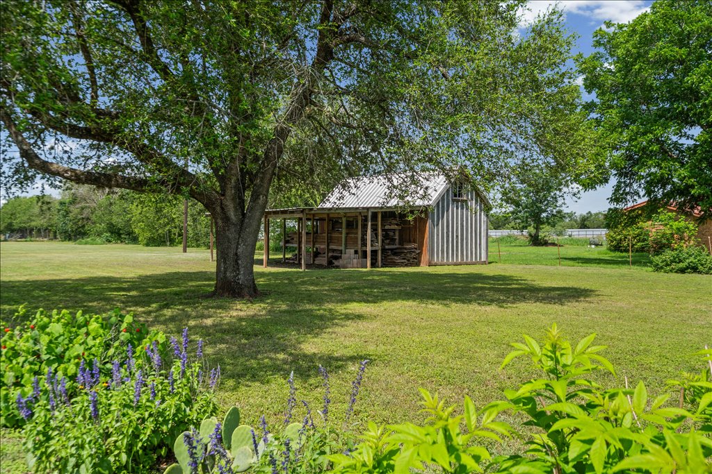 2421 Post Oak Road Webberville, TX 78653 - Photo 32 of 36 You’ve got another smaller storage shed tucked behind a massive oak tree, framed by beautiful purple wildflowers and prickly pear cactus in the foreground. Everywhere you look on this property, there’s a scenic view.