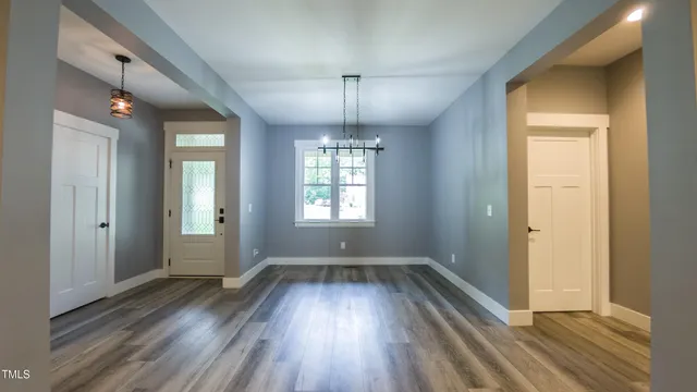 a view of an empty room with wooden floor fireplace and a window