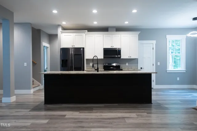 a kitchen with kitchen island granite countertop a stove a sink and a refrigerator