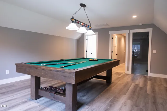 a room with wooden floor pool table and windows