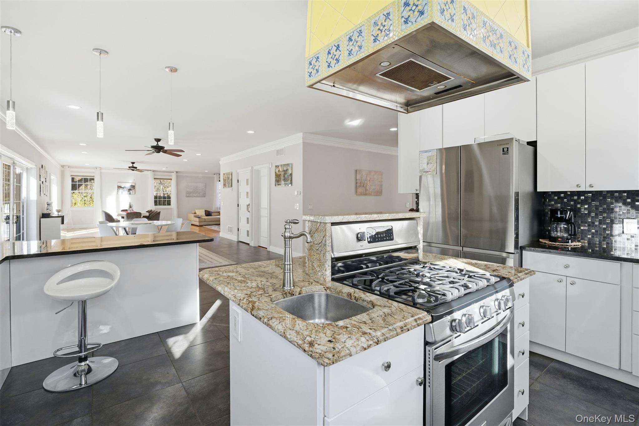 33 A Newtown Road Hampton Bays, NY 11946 - Photo 48 of 50 Kitchen with appliances with stainless steel finishes, extractor fan, open floor plan, a center island with sink, and white cabinetry
