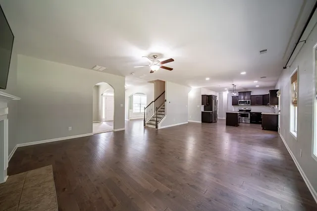a view of a livingroom with a fireplace a ceiling fan and windows