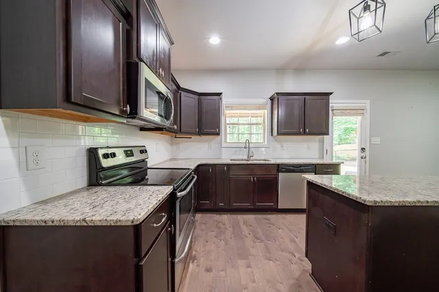 a kitchen with stainless steel appliances granite countertop a refrigerator a sink and a stove