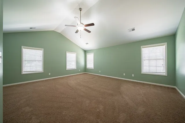 an empty room with windows and fireplace