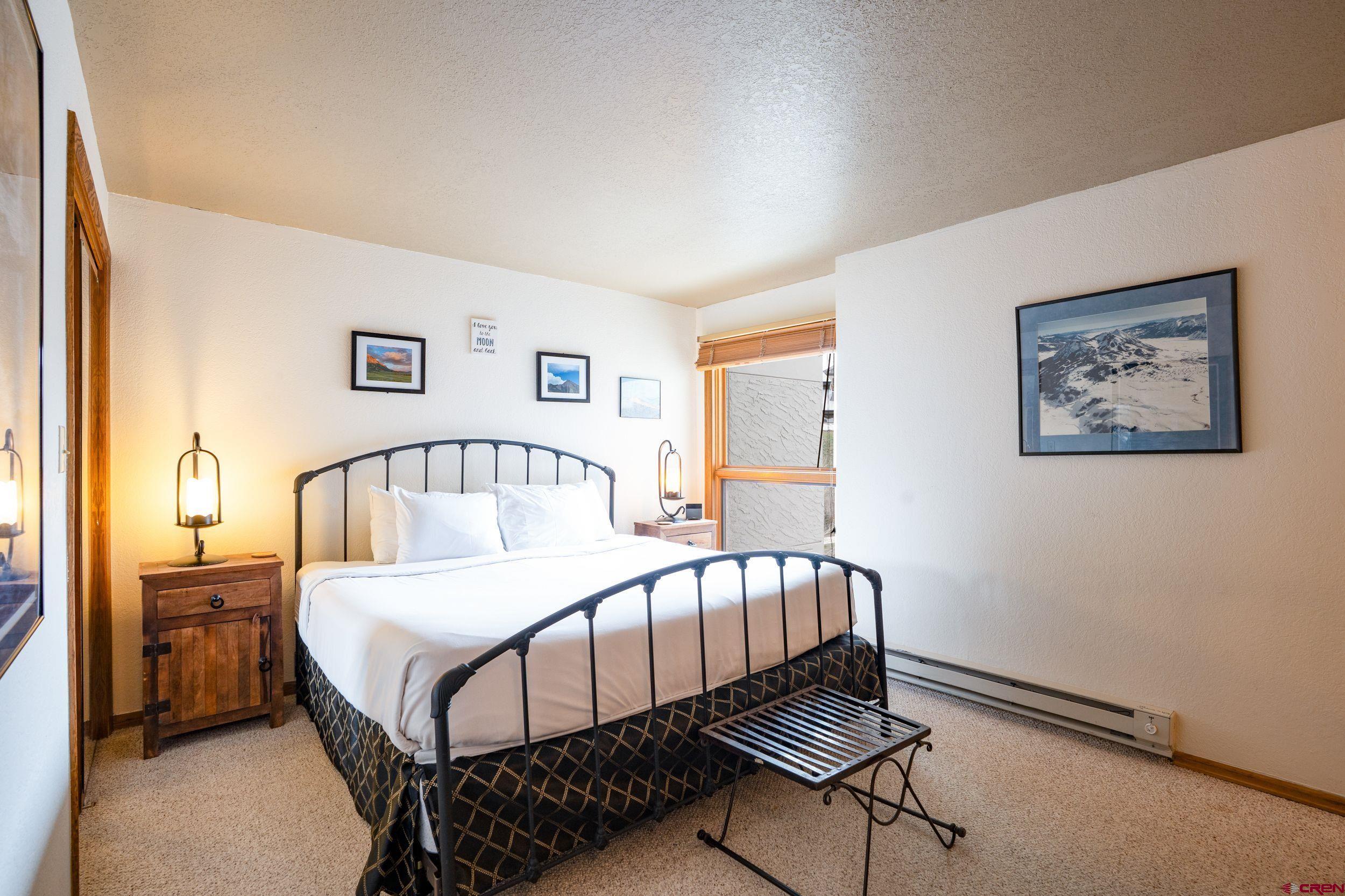 11 Snowmass Road, Unit 440 Crested Butte, CO 81225 - Photo 16 of 41 a bedroom with a bed and a dresser with wooden floor