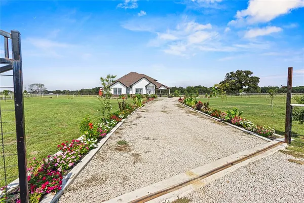 a view of a pathway both side of grassy field with shrub