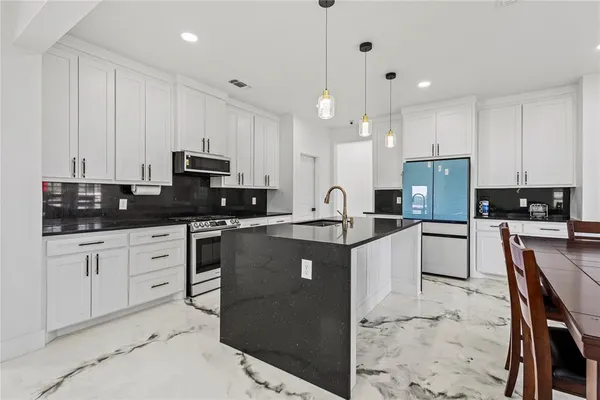 a kitchen with granite countertop a sink a counter top space stainless steel appliances and cabinets